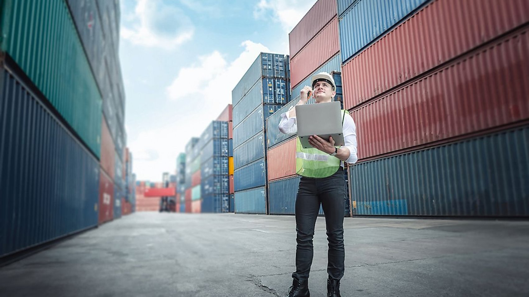 A transport engineer who manages the control of container placement via a laptop in a container yard.