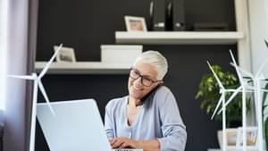 Senior Managerin, die im Büro telefoniert und auf dem Laptop schaut.