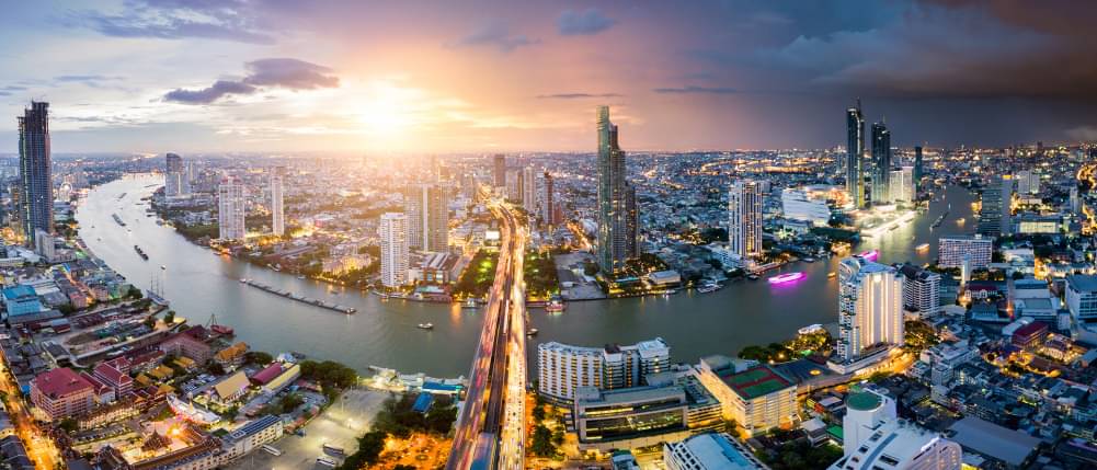 Luftaufnahme von Bangkok Skyline und Wolkenkratzer mit Lichtspuren auf Sathorn Road Zentrum des Geschäfts in Bangkok Innenstadt. Panorama der Taksin-Brücke über Chao Phraya Fluss Bangkok Thailand bei Sonnenuntergang.