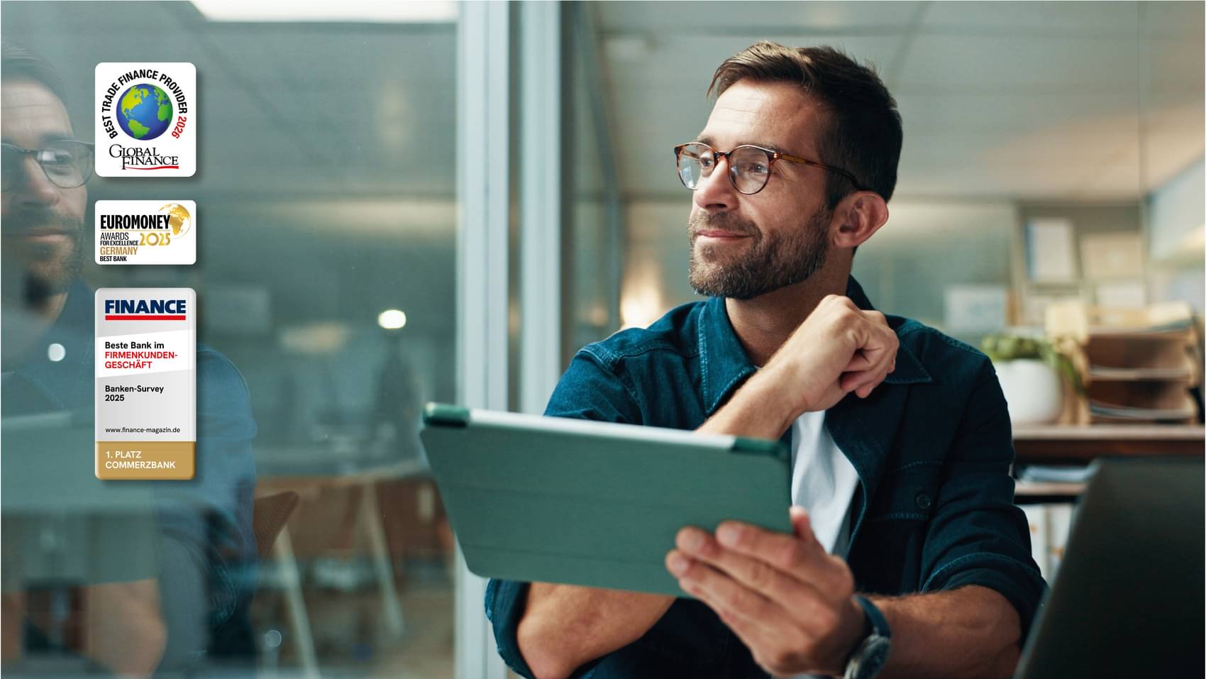 Geschäftsmann im Büro mit einem Tablet in der Hand, lächelnd und zur Seite blickend.