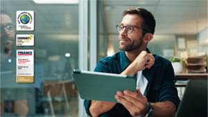 Geschäftsmann im Büro mit einem Tablet in der Hand, lächelnd und zur Seite blickend.