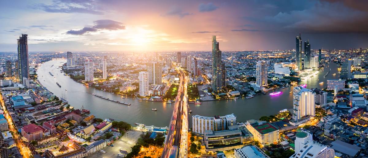  Aerial view of Bangkok skyline and skyscrapers with light trails on Sathorn Road center of business in Bangkok downtown. Panorama of Taksin Bridge over Chao Phraya River Bangkok Thailand at sunset.