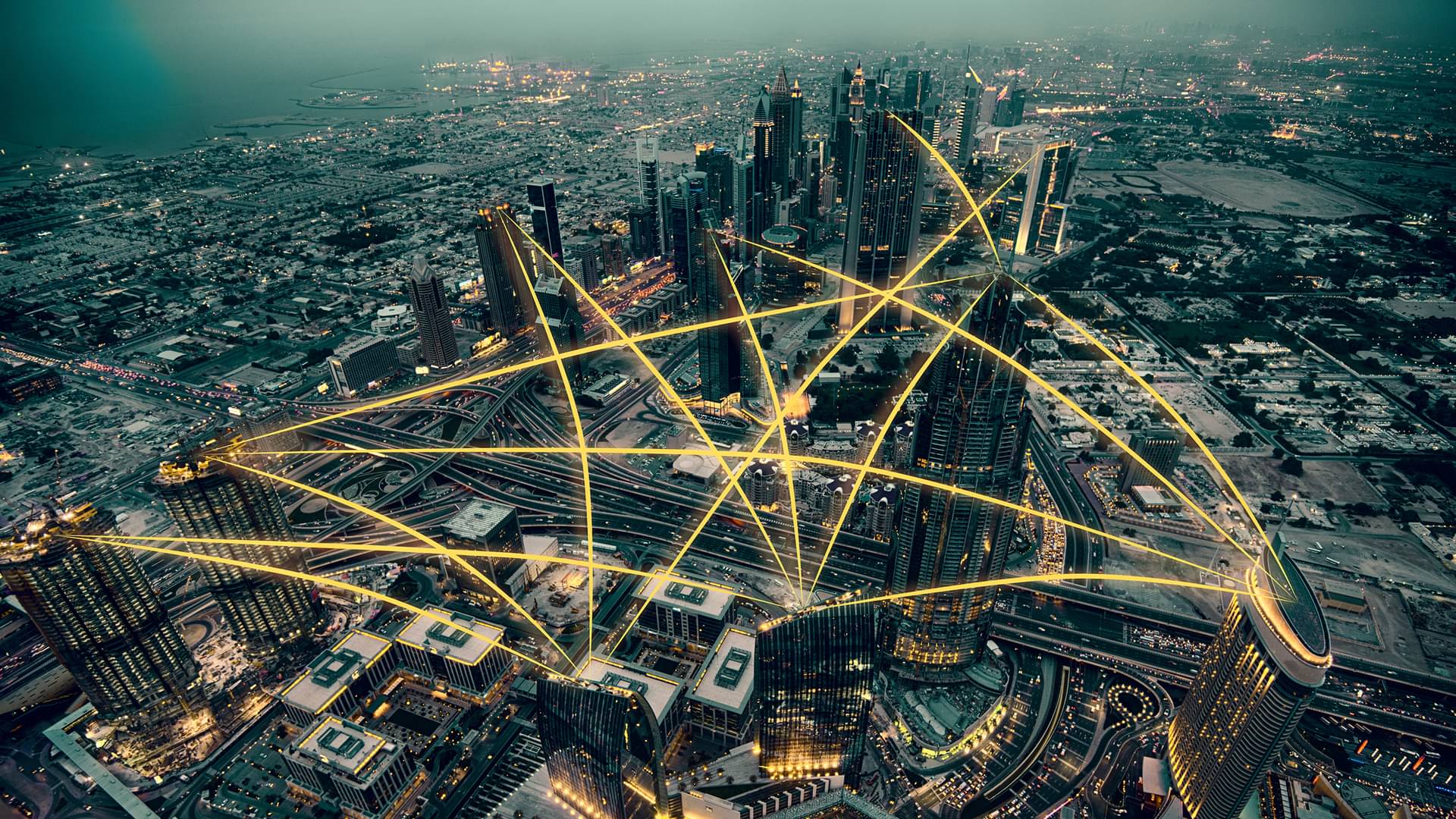 Luftaufnahme der Stadt bei Nacht mit gelben Linien von Hochhaus zu Hochhaus, als Verbindungskonzept für Infrastruktur