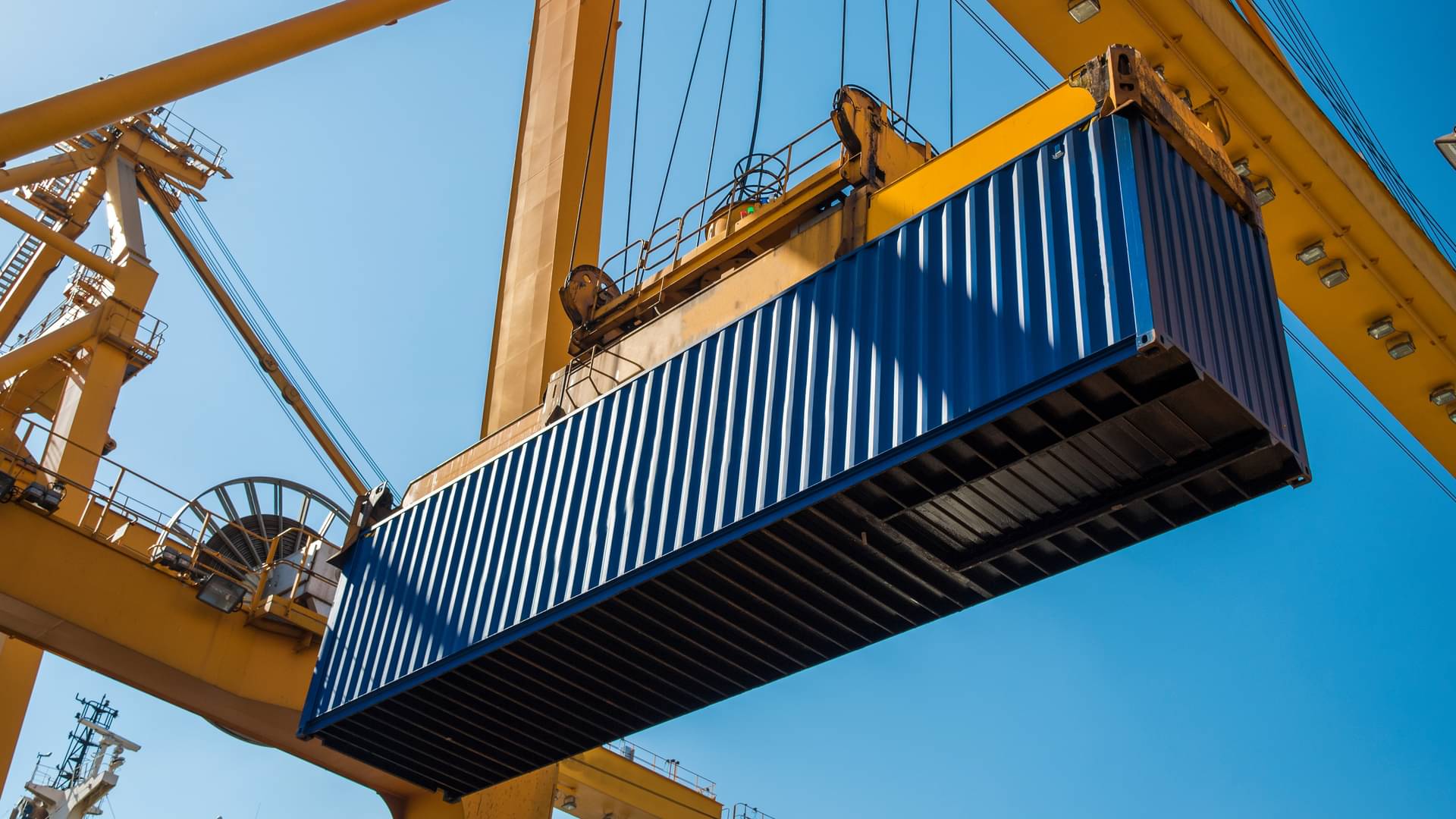 A large container is being lifted by a crane system.