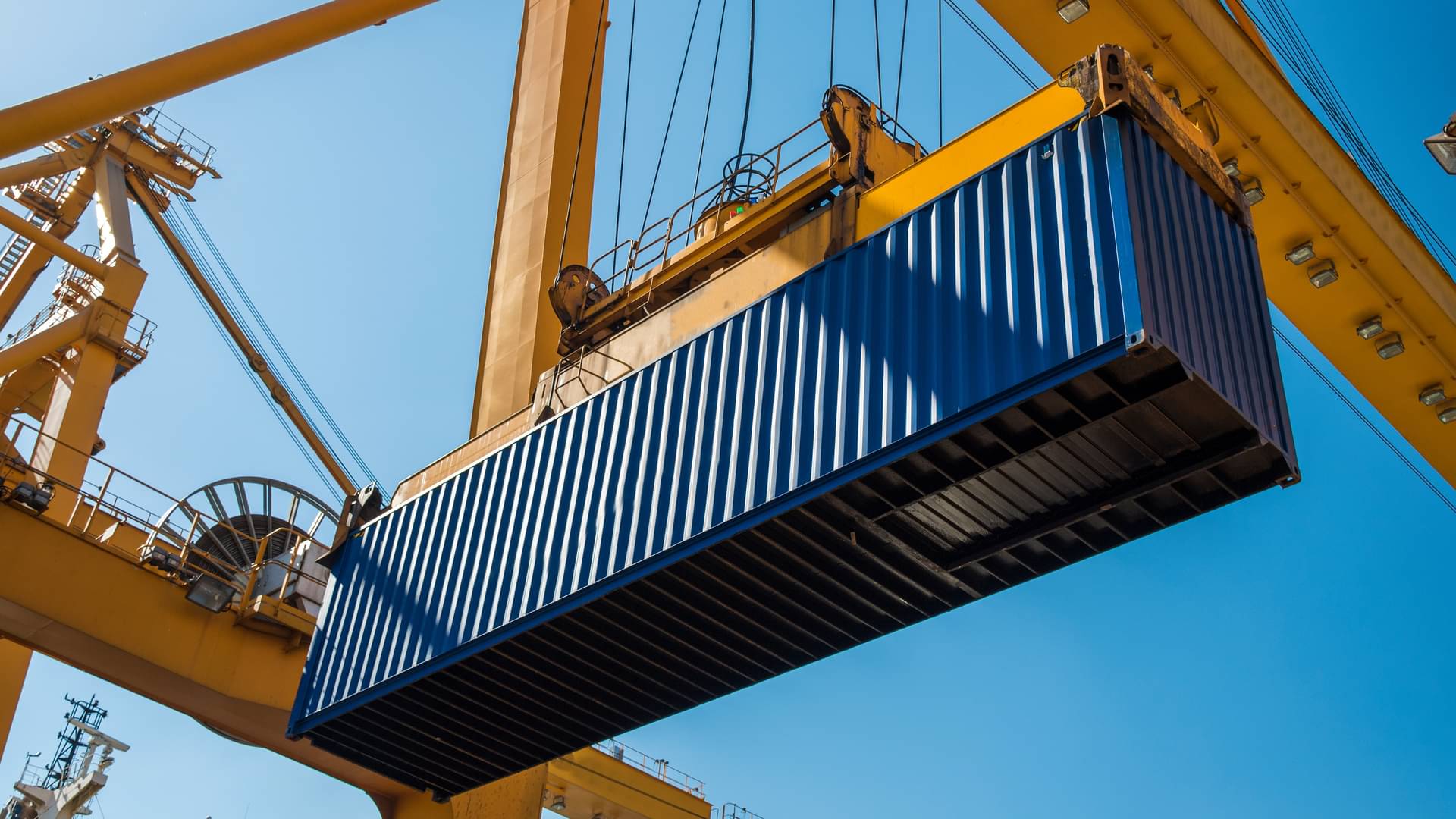 Ein großer Container wird von einer Krananlage angehoben.