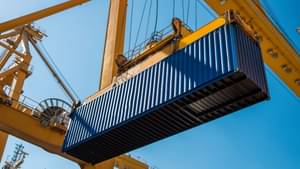 A large container is being lifted by a crane system.