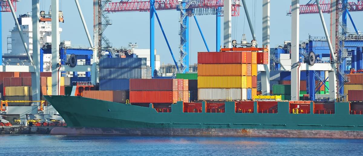 Containerhafen und Schiff unter Kranbrücke bei der Beladung